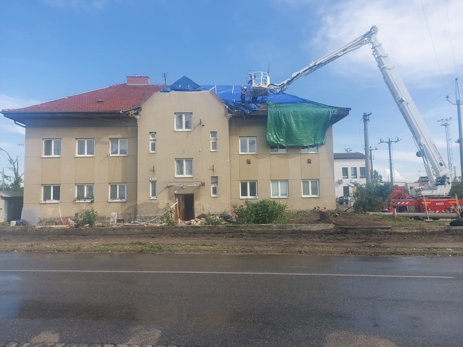 022 - hasiči pomáhají zakrýt poničené domy.jpg