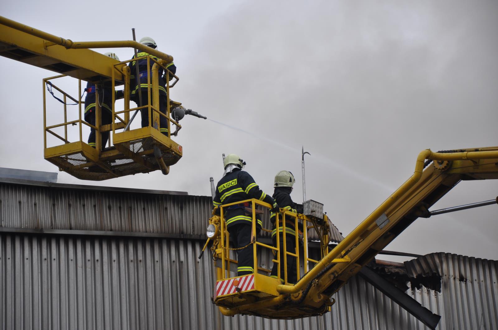 27_KHK_Požár Mileta_hasiči na plošinách hasí střechu budovy.JPG