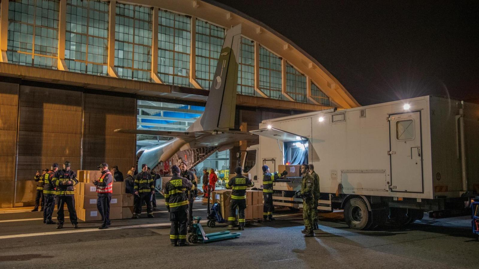 Hasiči nakládají humanitární pomoc do vojenského speciálu.jpg