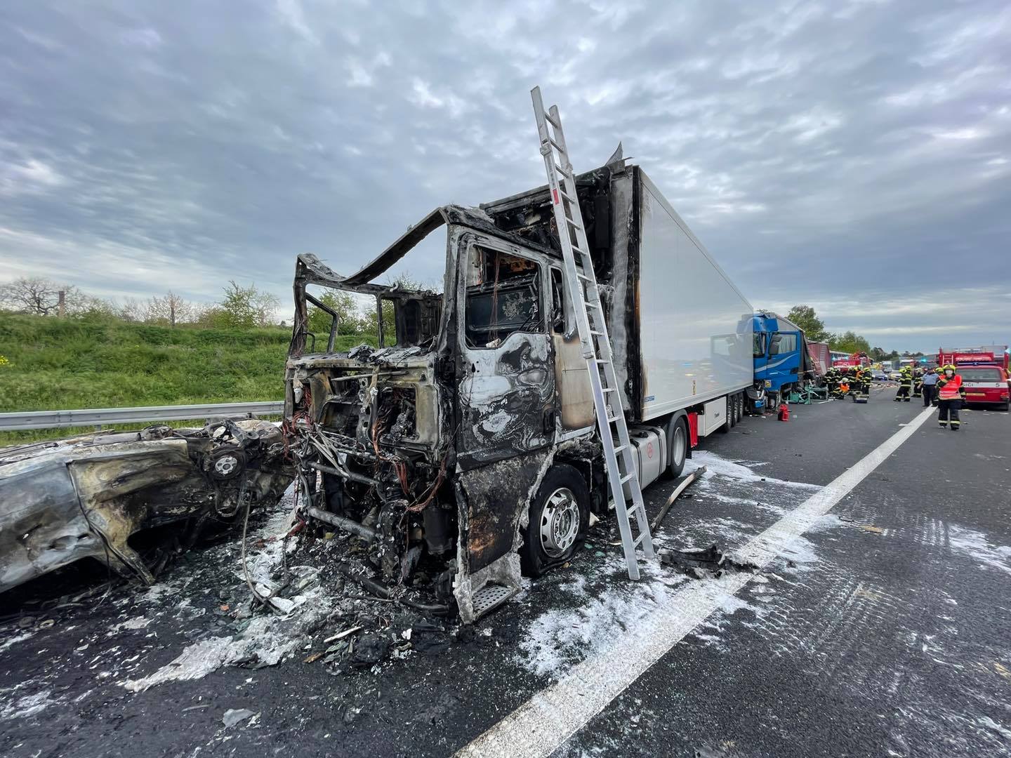 PHA_DN na dálnici D11_Pohled na ohořelé a nabourané vozy a zasahující jednotky hasičů.jpg