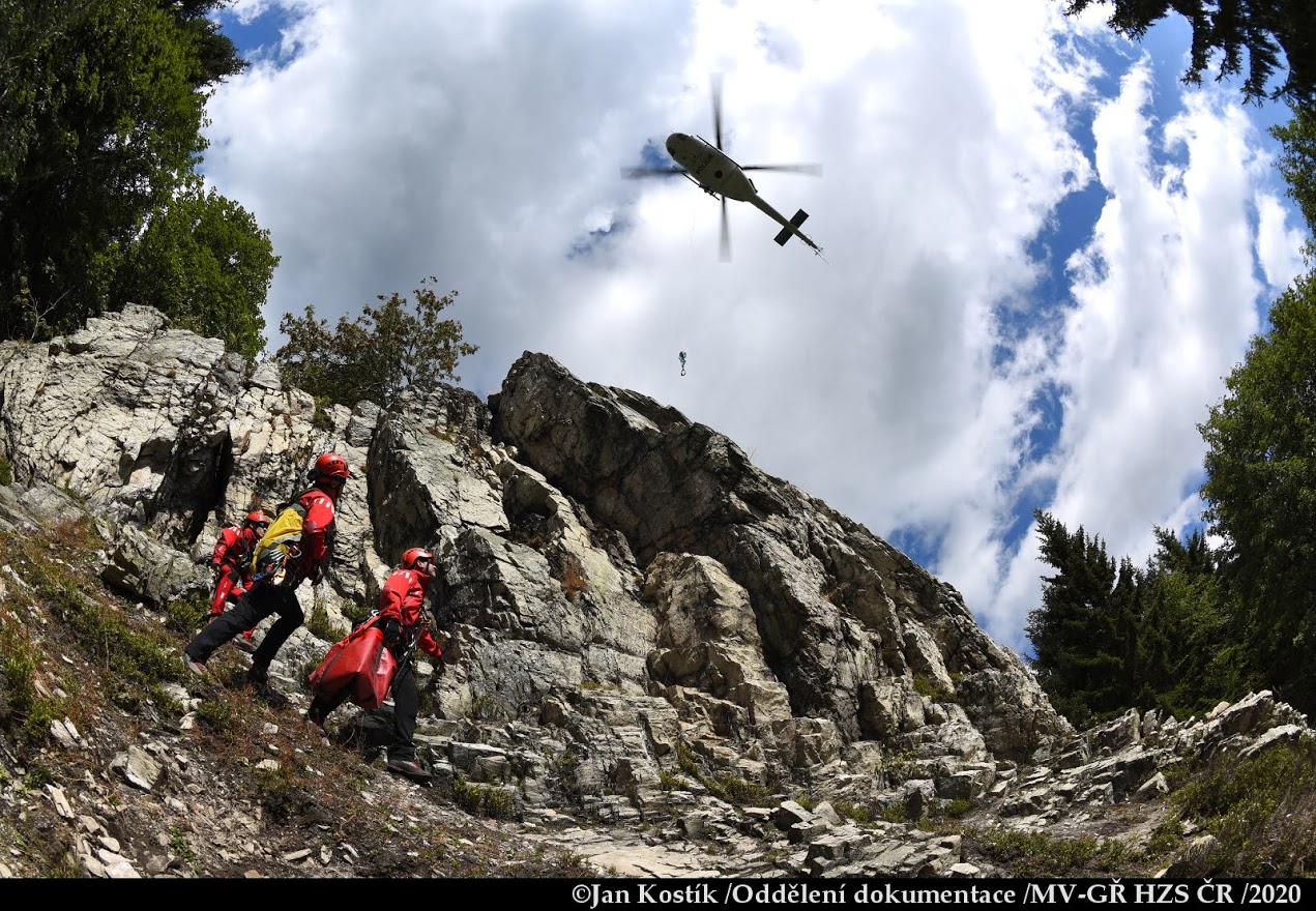 PHA_výcvik leteckých záchranářů_3 záchranáři sledují přibližující se vrtulník ke skále.JPG