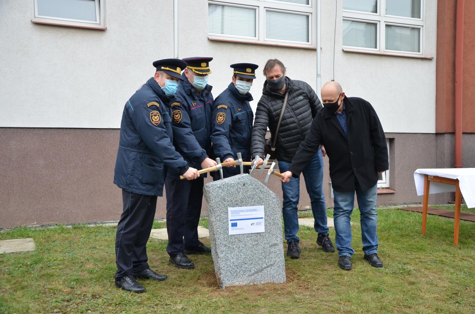 Účastníci poklepávají kladívky na základní kámen.jpg