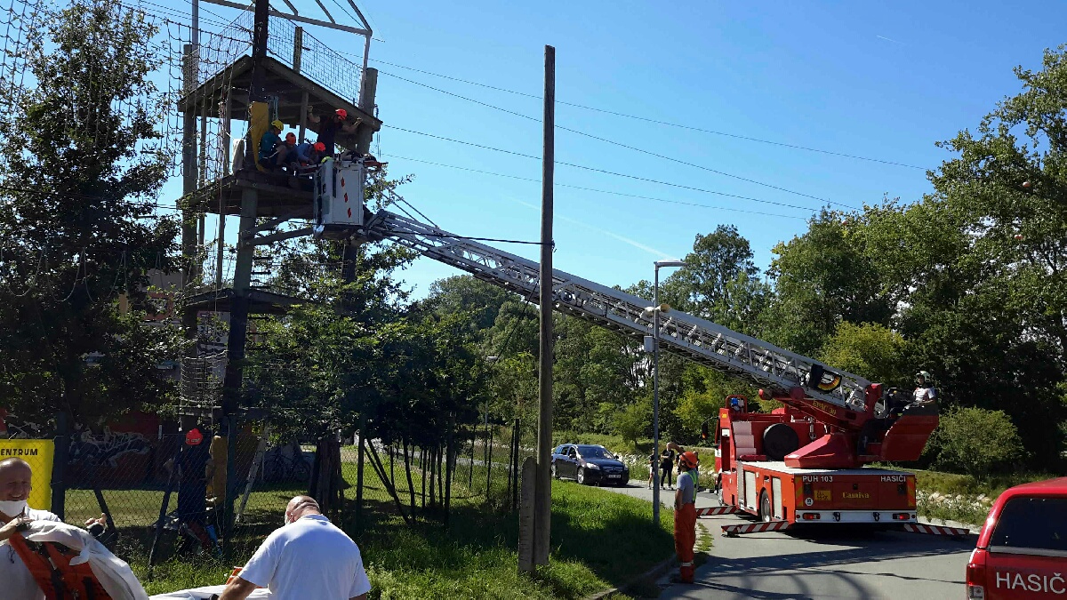 Hasič na plošině sundává zraněnou ženu z atrakce v lanovém parku.jpg