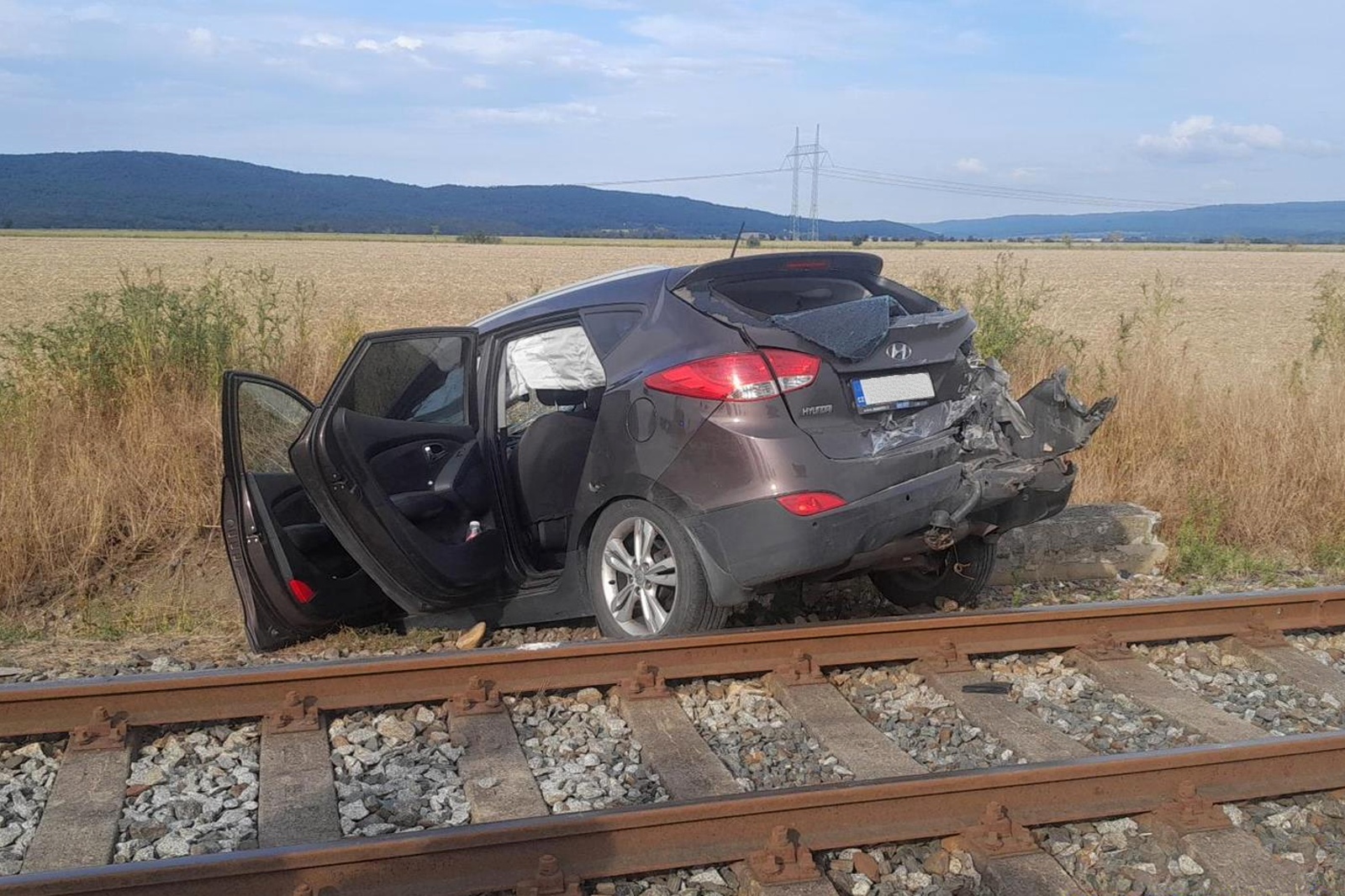 250725-Osobní automobil po střetu s motorovým vlakem na přejezdu nedaleko obce Neumětely na Berounsku.jpg